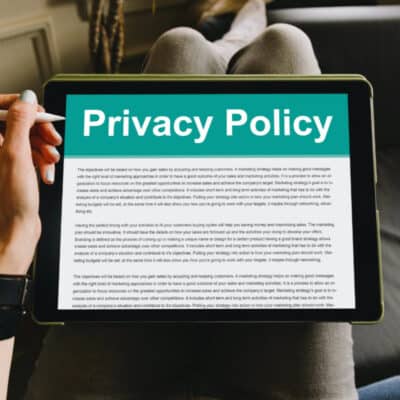 A woman holding an iPad on her lap with the image of a Privacy Policy on the screen.
